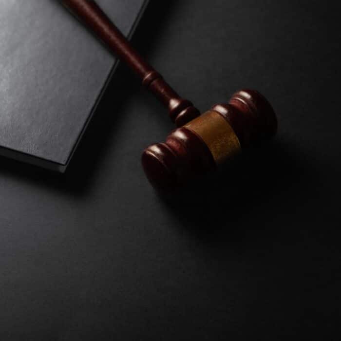 Wooden gavel resting on a dark surface next to book