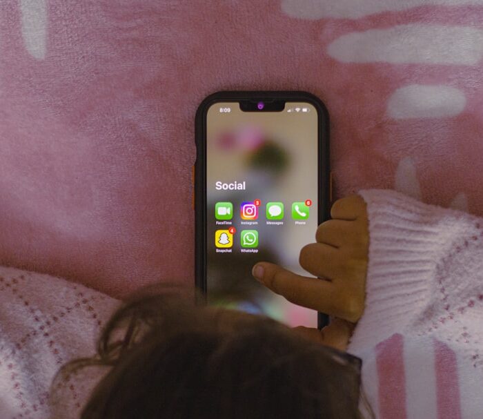 a person laying in bed holding a cell phone