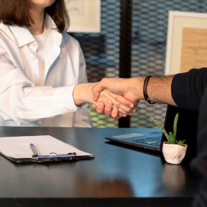 a man and a woman shaking hands in front of a laptop