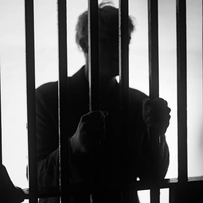 a man standing behind bars in a jail cell