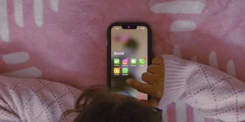 a person laying in bed holding a cell phone