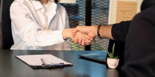 a man and a woman shaking hands in front of a laptop
